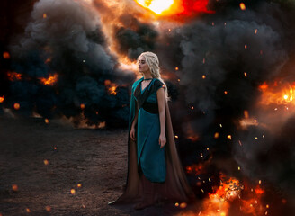 Fototapeta premium Art photo. Fantasy woman queen, blonde hair in braids. Warrior princess girl stands on background of black smoke, burning fire, flame war concept. Medieval costume, dress, cloak cape, leather armor.