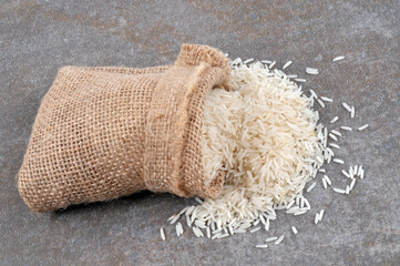 Fototapeta na wymiar Sac de riz cru renversé sur un fond gris