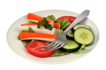 Assiette de surimi, tomate et concombre avec une fourchette sur fond blanc