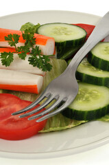 Assiette de surimi, tomate et concombre avec une fourchette en gros plan