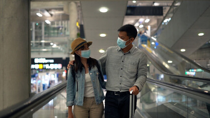 Couple traveler checking flight schedule board in airport terminal