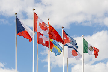 A few flags of various countries of the world flutter in the wind, against a cloudy sky. Flags of different states together - as a symbol of world cooperation. Various flags on flagpoles