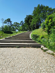 A view from below of a wide stone staircase in the Summer Garden of the city of Kronstadt against the background of a cloudless sky