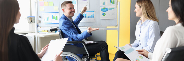 Disabled man in wheelchair showing graphs on chalkboard to his students