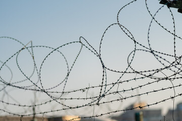 Barbed wire on the background of the sky at sunset close-up