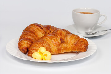 Italian breakfast. Two croissants, butter and a cup of espresso coffee on a white background.
