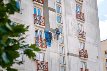 Rope access job, construction team repair and restore facade of high building. Workers works at...