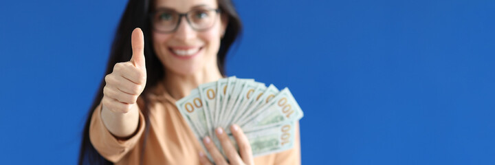 Young woman holding lot of money and showing thumb up closeup © H_Ko