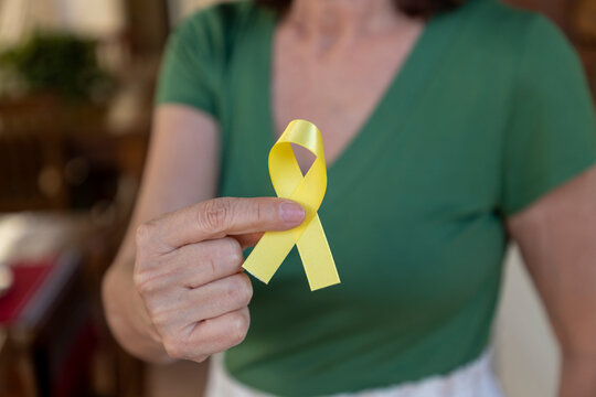 elderly woman holding yellow suicide prevention campaign ribbon. Yellow September. - Powered by Adobe