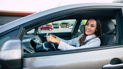Beautiful happy successful businesswoman is driving a new modern car in good mood.