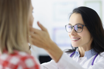 Woman doctor with glasses examining patient submandibular lymph nodes in clinic