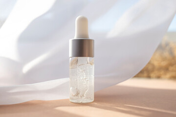 Cosmetic liquid glass bottle casts shadows. Close-up, side view.