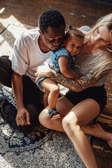 Little girl and her two loving parents inside living room