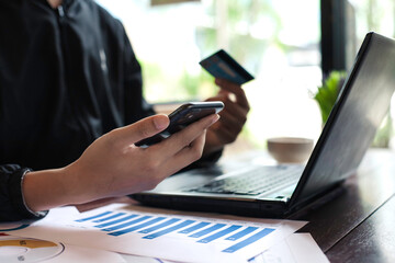Hands of a man working on a laptop with hot coffee in the morning.