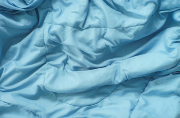 A flat lay image of a wrinkled, wrinkled or spiral blue quilt used as a background image.