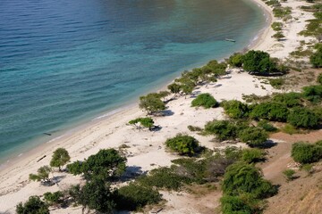 Scattered shrubs on the white sandy Cristo Rei back beach and beautiful turquoise water in Dili, Timor Leste, Southeast Asia