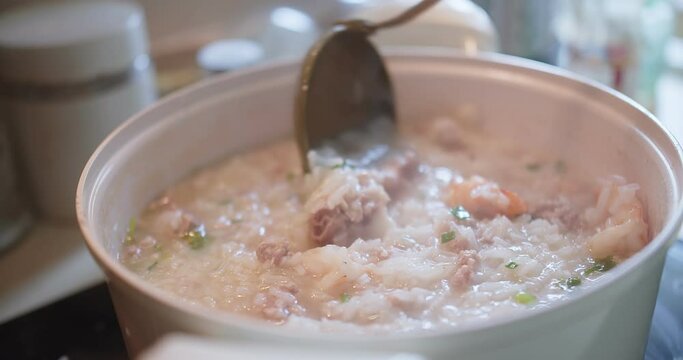 close up cooking stirring and holding Thai style food hot soft boiled rice with Pork Ribs at the kitchen, breakfast healthy food concept