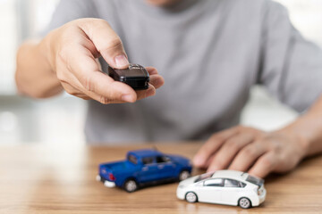 Close up hand of man holding and push remote control for lock and Un-lock car : concept model toy a car in blur background