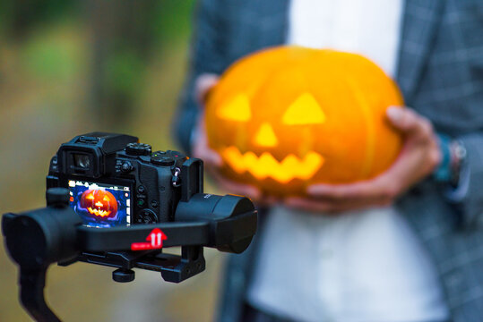 Professional videographer holding camera on 3-axis gimbal stabilizer making a halloween videos.