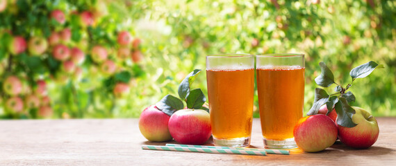 glasses of apple juice with fresh fruits on a wooden table