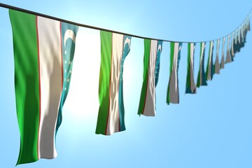 nice labor day flag 3d illustration. - many Uzbekistan flags or banners hanging diagonal on string on blue sky background with selective focus