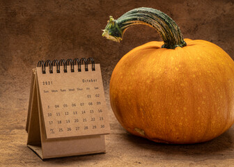 October 2021 - spiral desktop calendar with a pumpkin, time and business concept