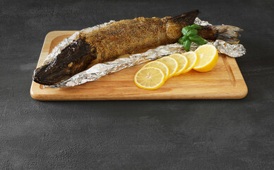 baked stuffed pike on a foil on a cutting board . place for text   