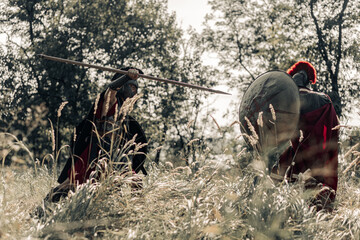 Battle with spear and sword between two ancient warriors on meadow.
