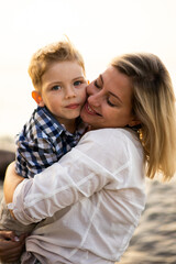 Family at the summer vacation. Mother and son hugging and kissing at the seaside