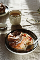 Cinnamon swirl brioche or Cinnamon roll bun and cups of cocoa on greige linen tablecloth. Homemade baked swedish cinnamon roll. Kanelbullar. Cozy winter breakfast