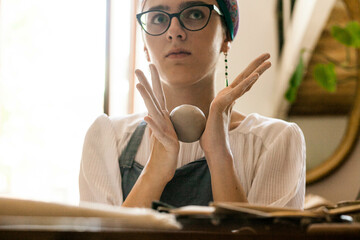 Woman  in a ceramic workshop makes dishes, daylight, half-length portrait
