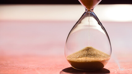 Gold Sand running through the bulbs of an hourglass measuring the passing time in a countdown to a...