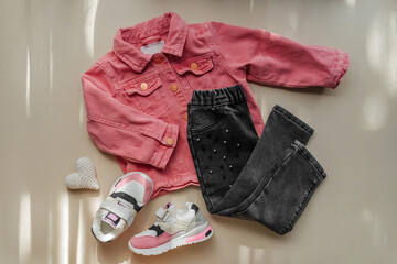 Pink jeans jacket  and pants with sneakers. Set of baby clothes and accessories for spring, autumn or summer on  white background. Fashion kids outfit. Flat lay, top view