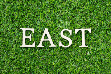 Wood alphabet letter in word east on green grass background