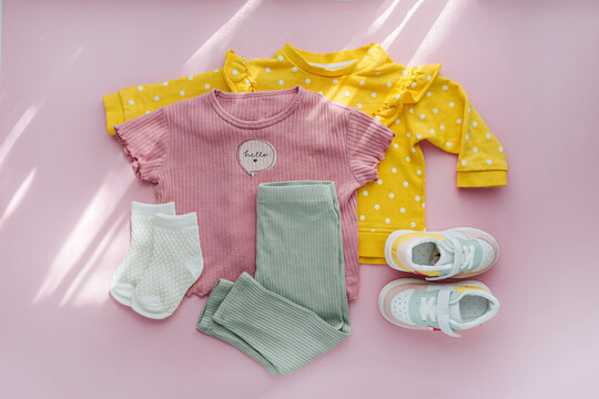Jumpers  and pants with sneakers. Set of baby clothes and accessories for spring, autumn or summer on  pink background. Fashion kids outfit. Flat lay, top view