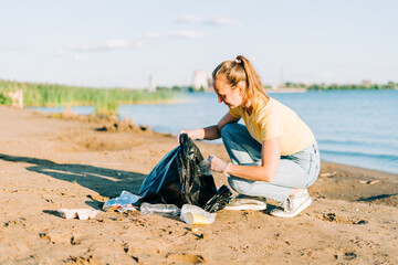 Young female volunteer satisfied with picking up trash, a plastic bottles and coffee cups, clean up beach with a sea. Woman collecting garbage. Environmental ecology pollution concept. Earth Day.