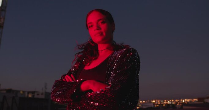 portrait beautiful woman posing with arms crossed at night looking confident with red light in city