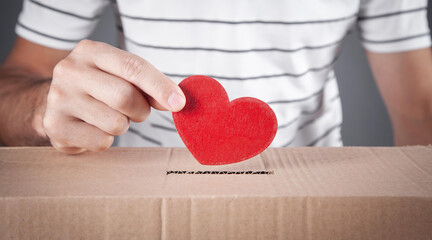 Male hand putting red heart in box.