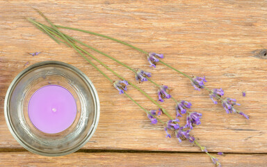 Obraz na płótnie Canvas Scented candle and lavender flowers on a wooden table.