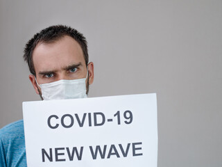 A man of Caucasian nationality in a medical mask on the background of a leaflet with the...