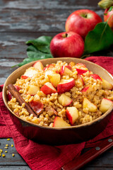 Baked bulgur with apple, honey and cinnamon in a bowl on a dark wooden background. Sweet bulgur porridge. Tasty breakfast, vegan food.