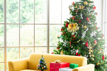 Modern living room and comfort yellow sofa with christmas tree and presents. Beautiful holiday decorated room. Winter season outside window.