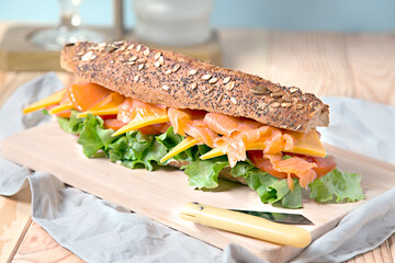 bocadillo con pan integral y semillas con salmón ahumado,  queso cheddar y lechuga