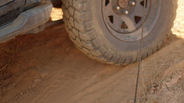 Closeup of the big wheel ofa suv that is driving on sandy clay terrain. Concept of traveling by car on the desert