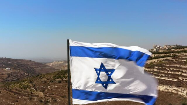 Israeli flag on the background of Judea and Samaria. Sunny day overlooking rare settlements in the desert. UHD video
