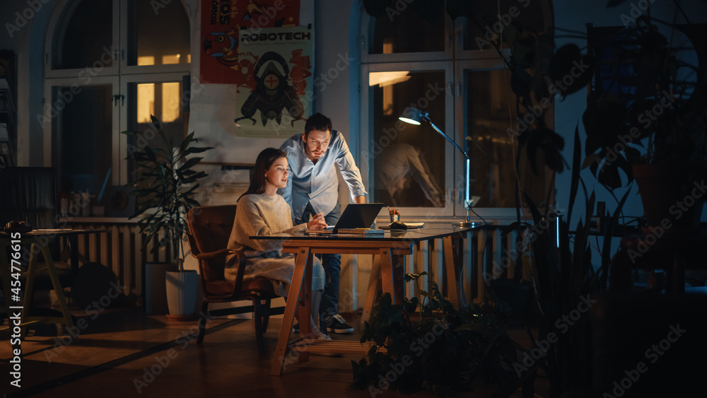 Poster art director and marketing manager discussing work-related projects on a laptop computer in creative