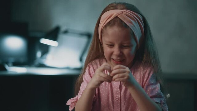 Assiduous long haired little girl with pink headband tries to open pill bottle to cure younger brother in semi-dark room at home extreme close view slow motion