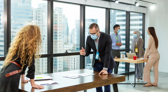 Group of corporate colleagues wearing face mask meeting in the modern office.