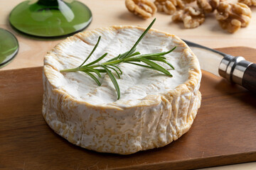Traditional whole soft raw milk French Camembert cheese close up on a cutting board 