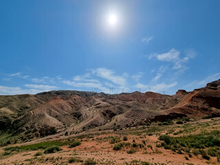 Multicolored mountains with peaks in clear sunny weather against the blue sky.